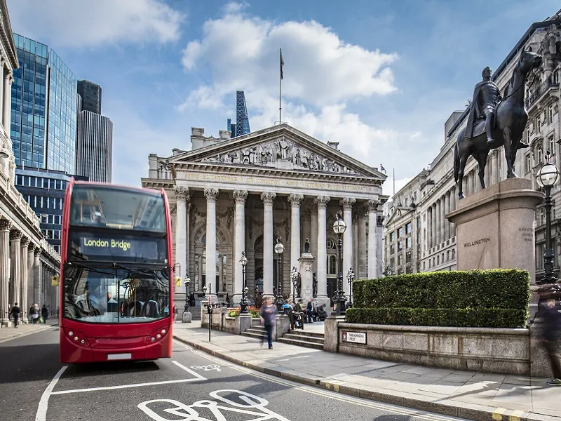 Bus waiting in front of the London Stock Exchange on a sunny day.