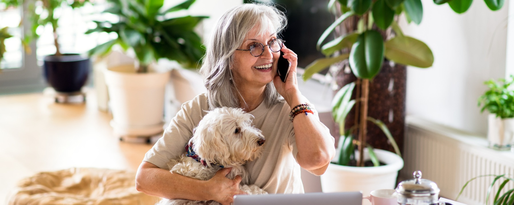 customer experience - mature woman on the phone with paperwork smiling- 1800*720