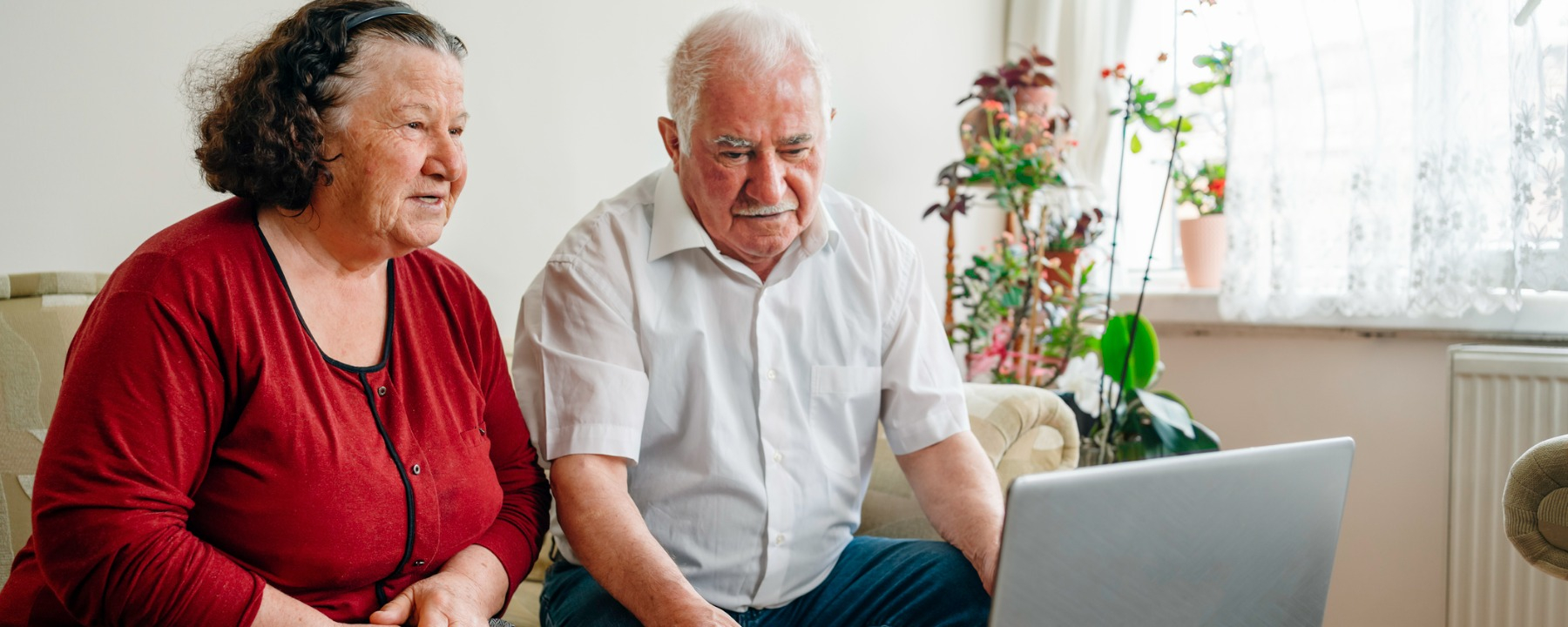 Welfare and employability- older couple at home looking at laptop- 1800*720
