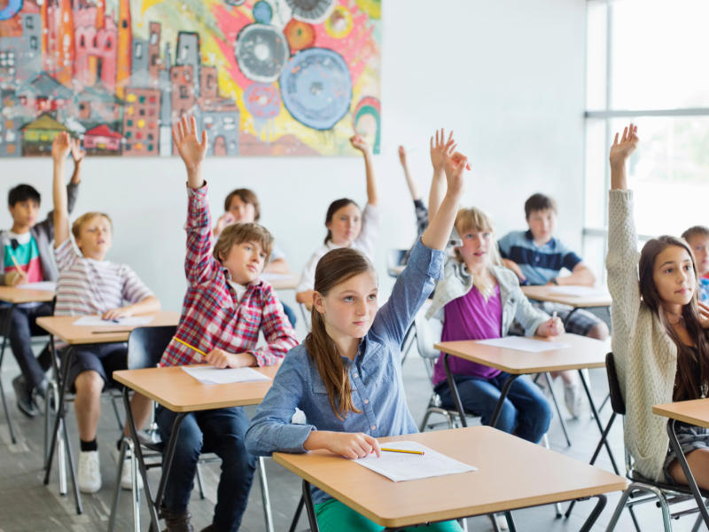 Students with arms raised in classroom