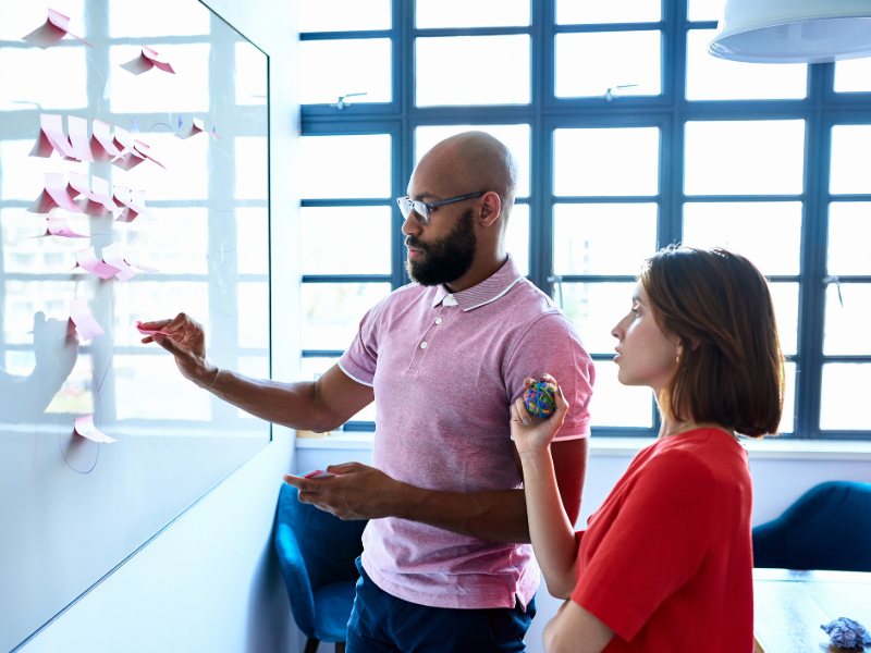 Coworkers planning with notes on whiteboard