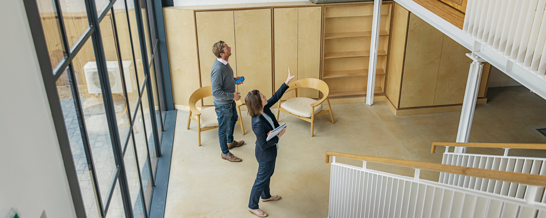 Female property agent showing man around empty office space