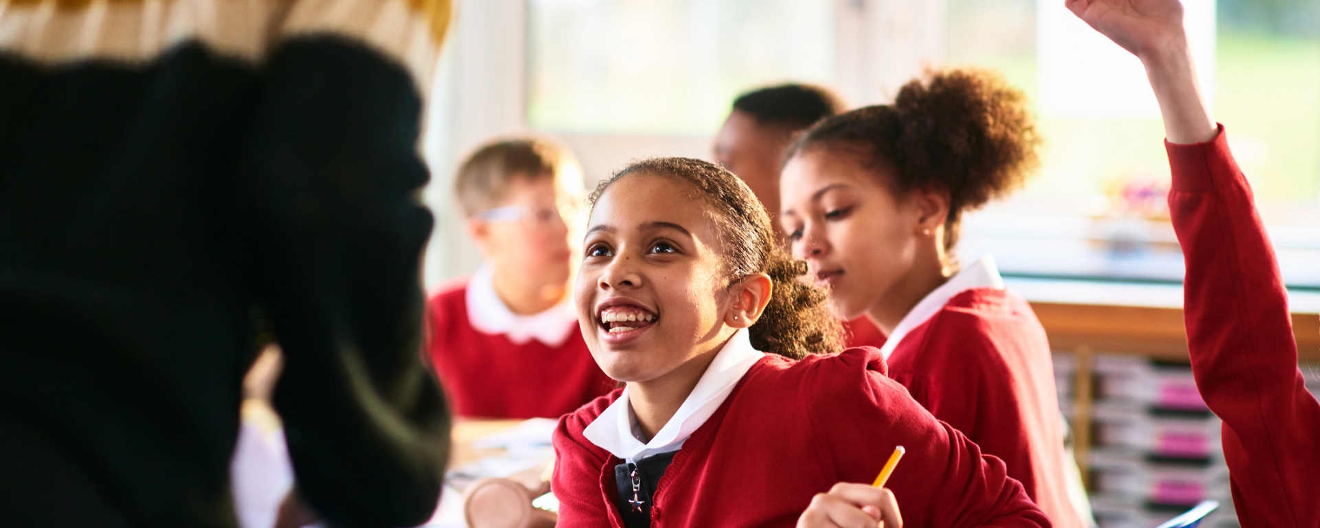 girl-smiling-and-listening-to-teacher-in-primary-class