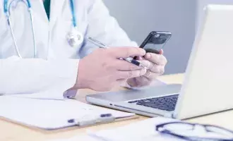 Healthcare professional using laptop and mobile