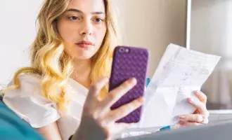 Woman using phone looking at bills