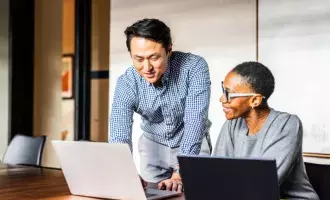 Business colleagues working on laptops in modern conference room