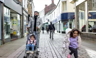 father-enjoying-a-stroll-through-a-pedestrian-shopping-street-with-his-child