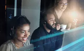 Three people at desks with headsets and blurred monitors.