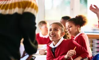 Girl smiling and listening to teacher in primary class