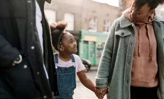 Happy black family walking daughter in city 
