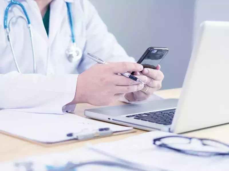 Healthcare professional using laptop and mobile