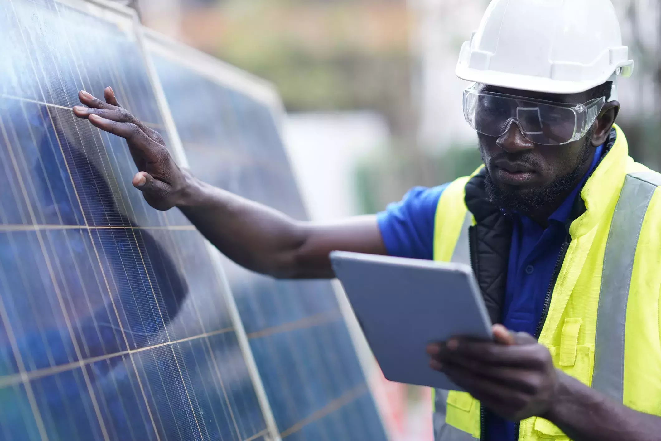 Capita Climate Change Hub Man looking at tablet while touching a solar panel