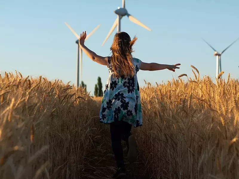 Road to Net Zero report Girl running towards wind turbines