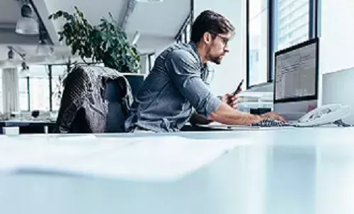Investor news, events and alerts | Capita Business man in office looking at computer