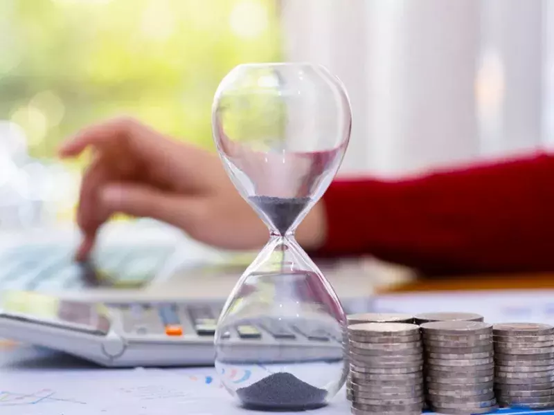 Financial management Hourglass and coins on a desk