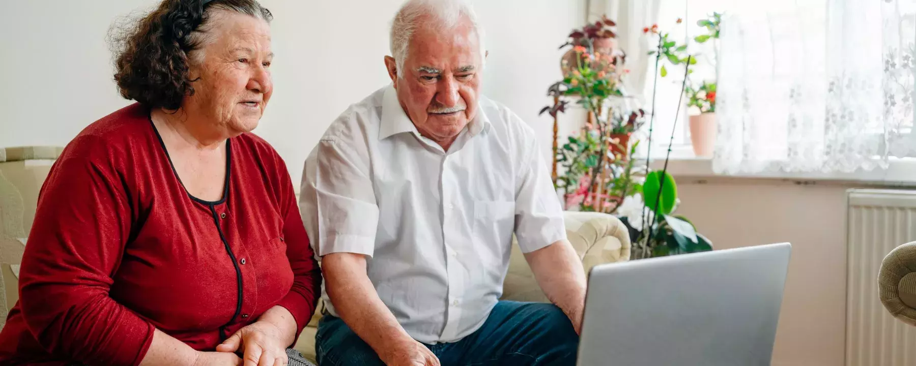 Local government - older couple at home looking at laptop