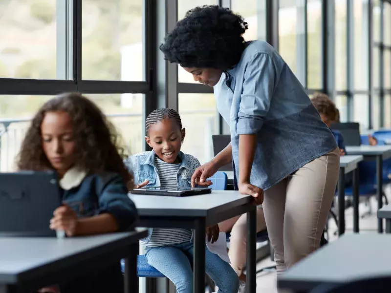 Teacher assisting girls in classroom